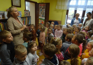 p. Dyrektor Miejsko- Gminnej Biblioteki Publicznej w Kleczewie Magdalena Siupa z zaangażowaniem opowiada dzieciom stojącym wokół niej oraz pani dyrektor i pani Ani.